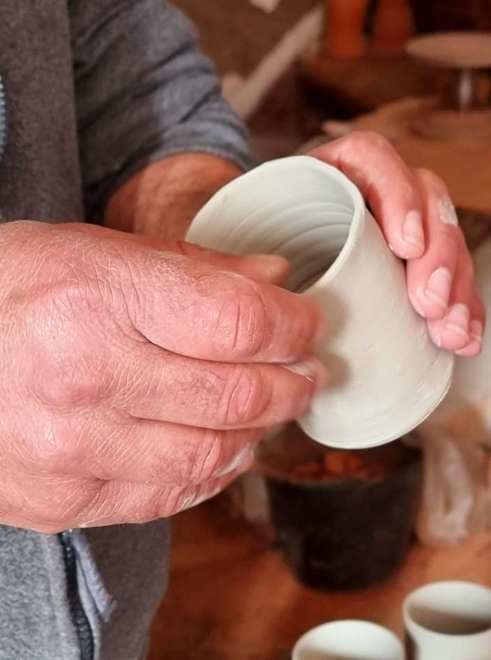 A potter’s hands shaping a jug on the wheel