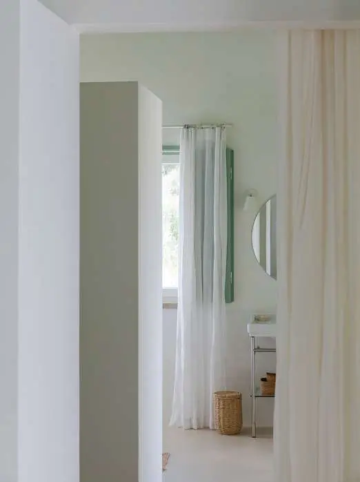 A bathroom beyond a linen curtain, seen from the bedroom door