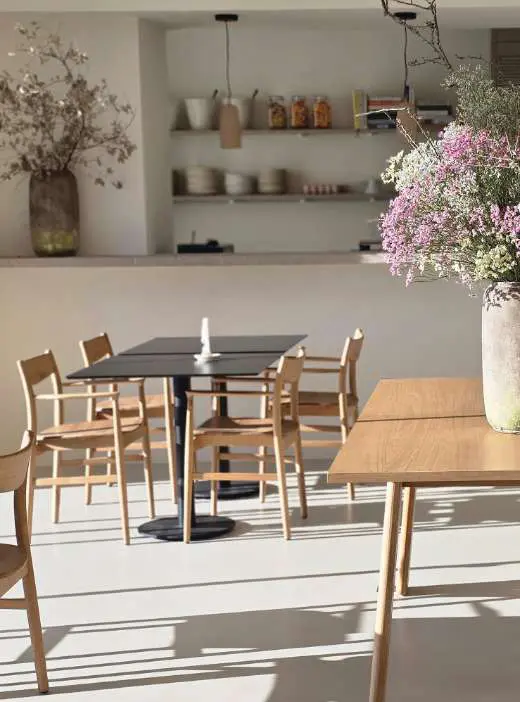 The kitchen dining room: open shelves, pale oak tables and tall vases of dried flowers