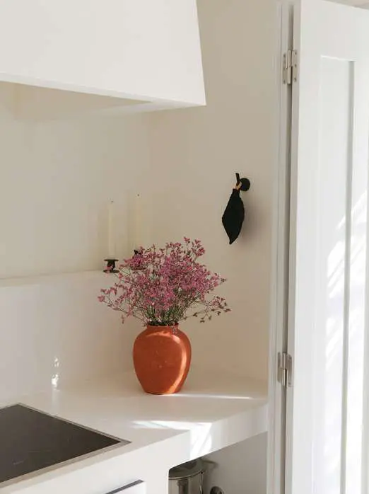 Pink blossom in a terracotta vase on a white kitchen counter