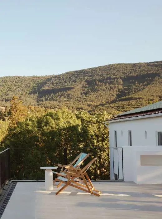 A wooden deckchair on the terrace, looking out over the wooded hills of the Serra